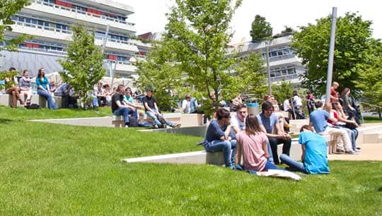 Studenten sitzen auf der Wiese vor der Universität Ulm