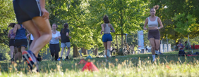 Fitness-Kurs in der Friedrichsau. Menschen joggen auf der Wiese im Sommer.