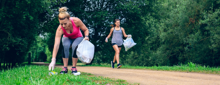 Zwei Frauen im Park joggen und sammeln Müll.