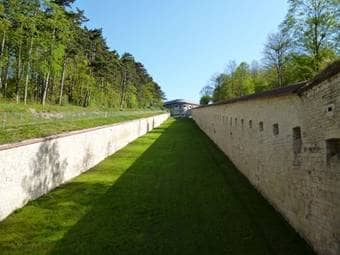 Entlang eines ehemaligen Festungsgrabens führen Steinmauern auf die Wilhelmsburg zu.