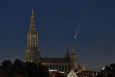 Am Nachthimmel über dem Ulmer Münster zieht eine Sternschnuppe vorbei.