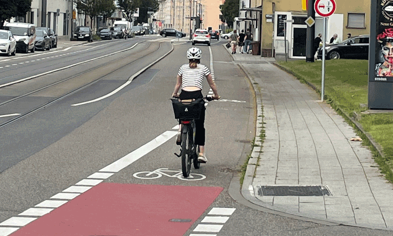 Eine Fahrradfahrerin fährt auf einem rot markierten Fahrradstreifen